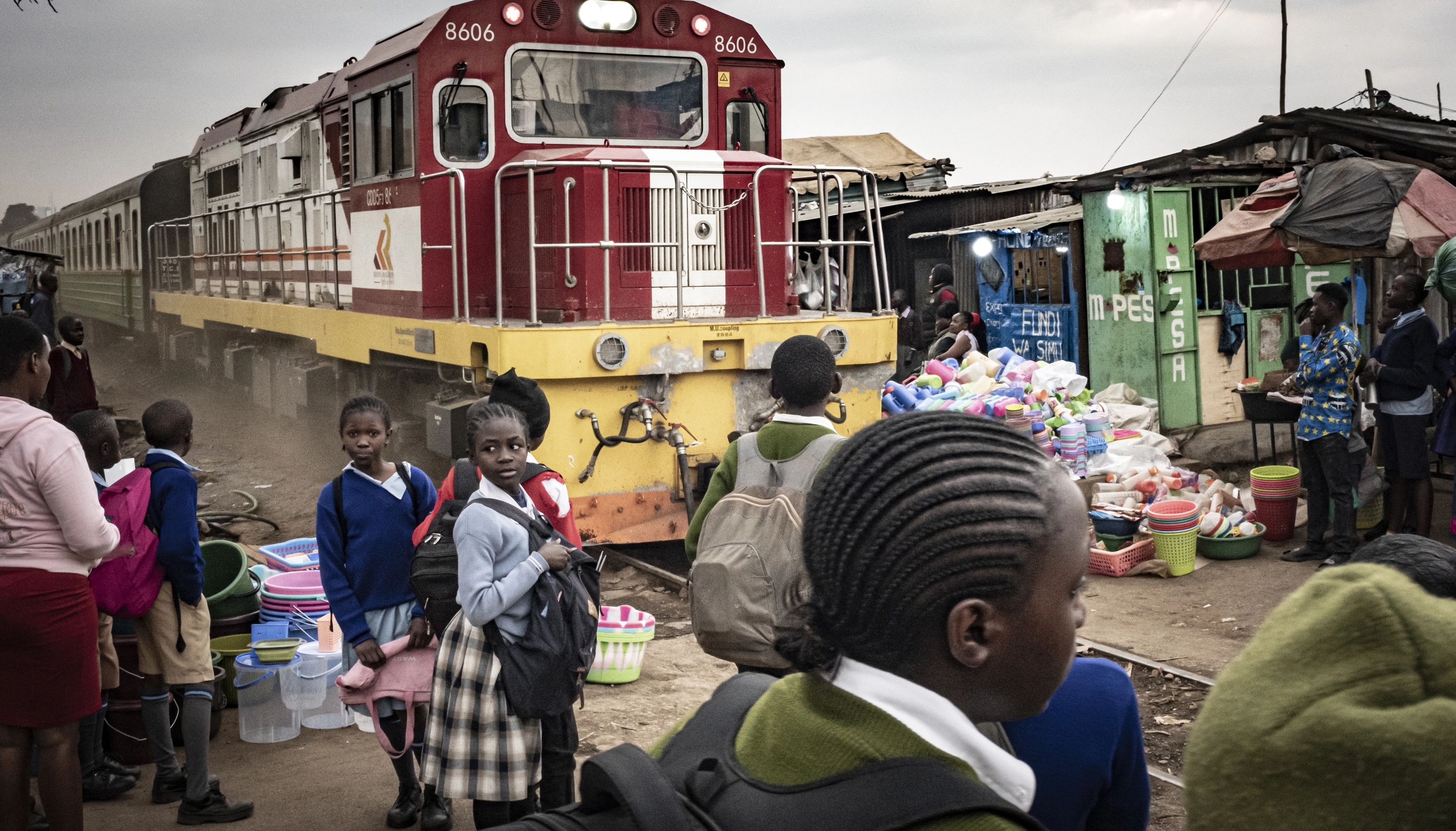 Schoolchildren weave through Kibera's busy streets as the commuter train links the settlement to central Nairobi.