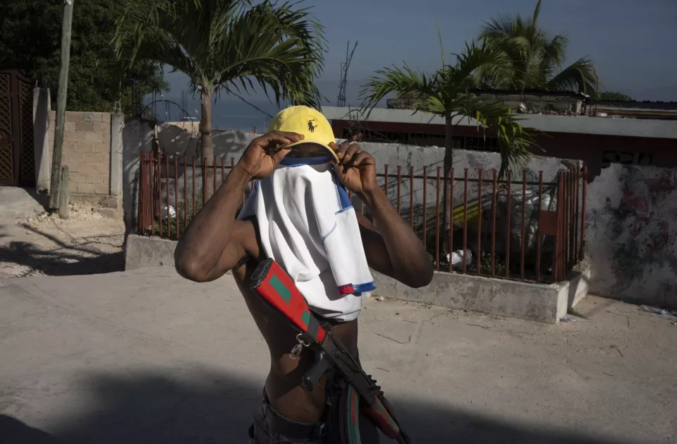 Person in white shirt and yellow cap holding rifle