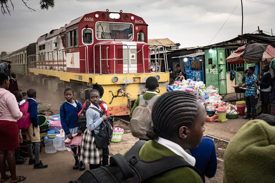 A red and yellow train at a station surrounded by students
