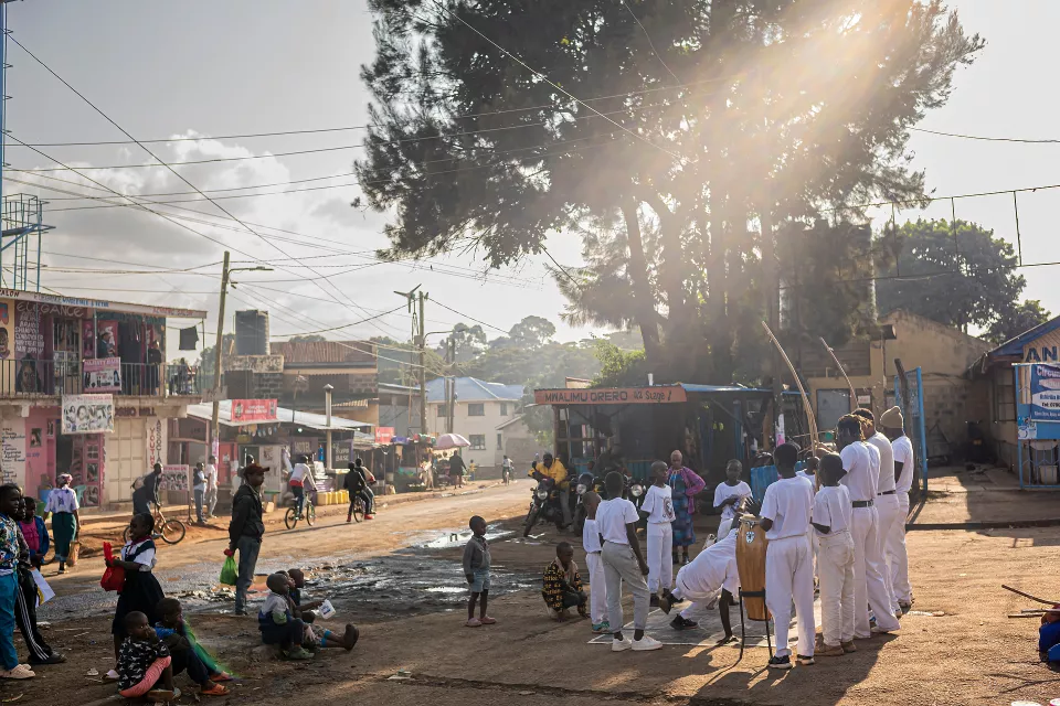 Street gathering with children in white uniforms standing in a circle holding hands