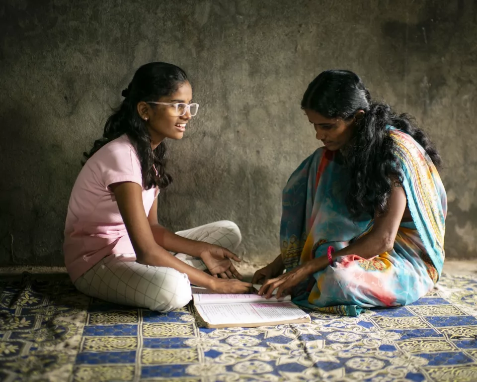 Two women sitting on patterned mat
