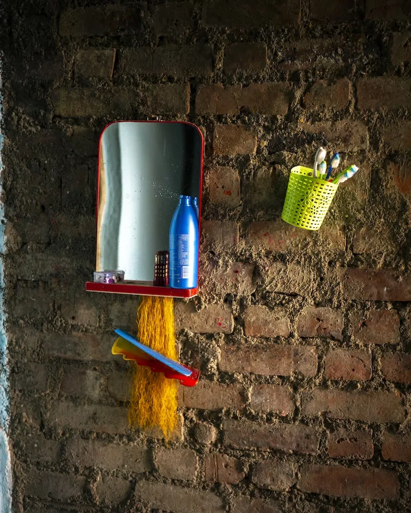 Small wall mirror with shelf holding blue bottle