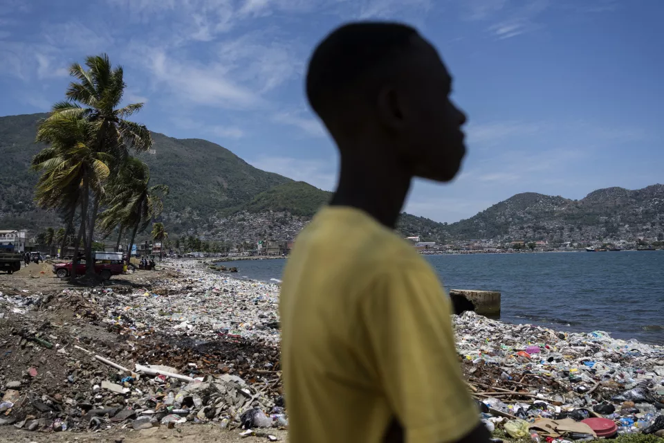 Silhouette of person in yellow shirt standing on beach looking toward bay
