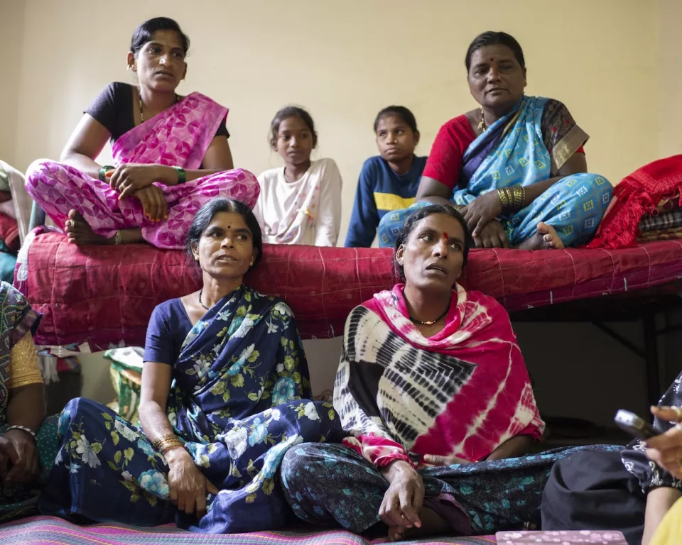 Group of women and children sitting together in yellow-walled room