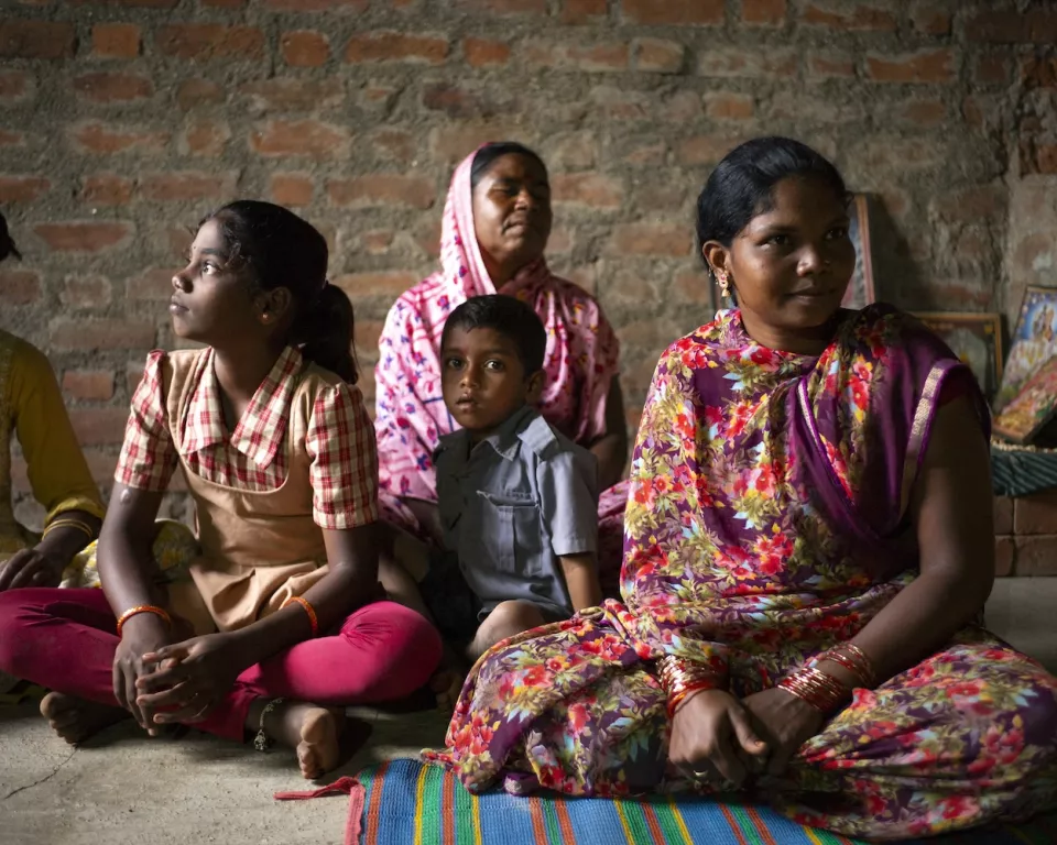 Four people seated indoors against brick wall