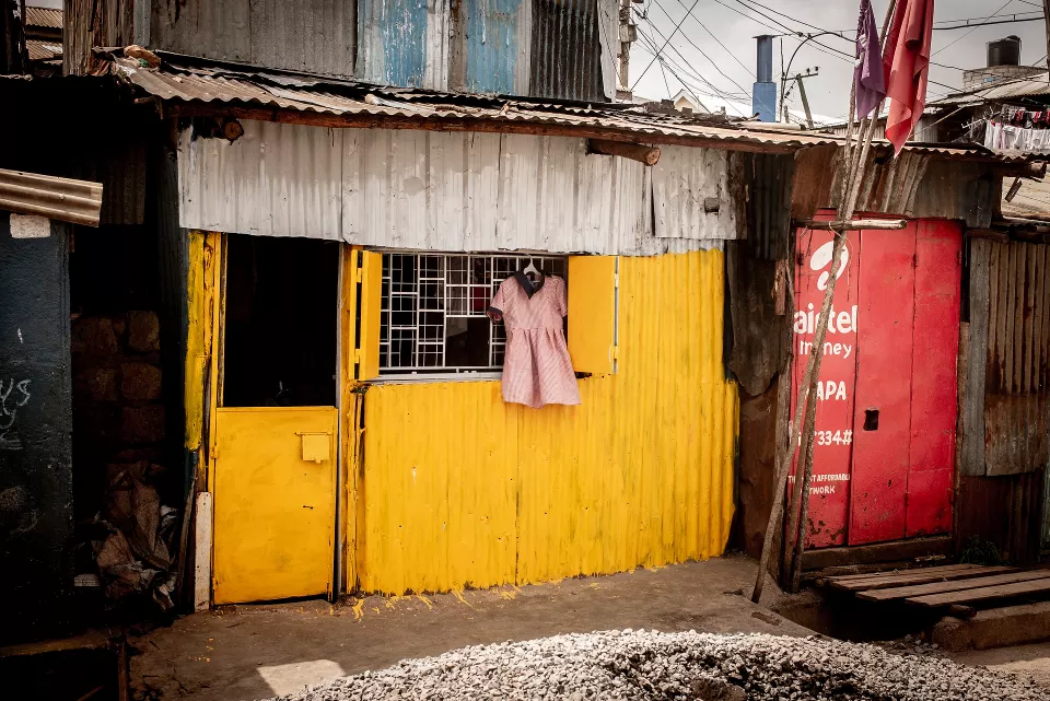 Bright yellow corrugated metal storefront with pink dress hanging on the window
