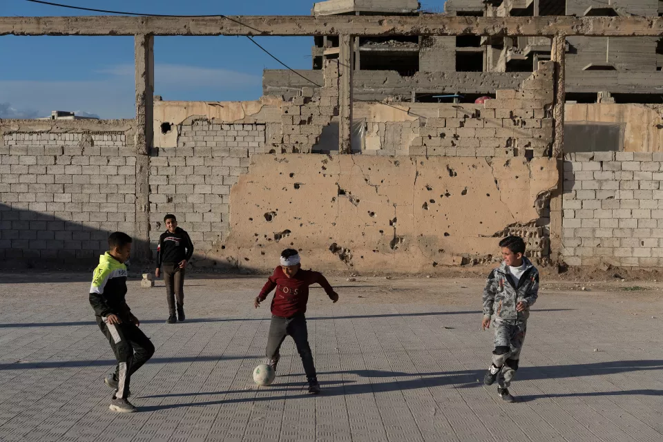four young boys are playing soccer in the middle of ruins 