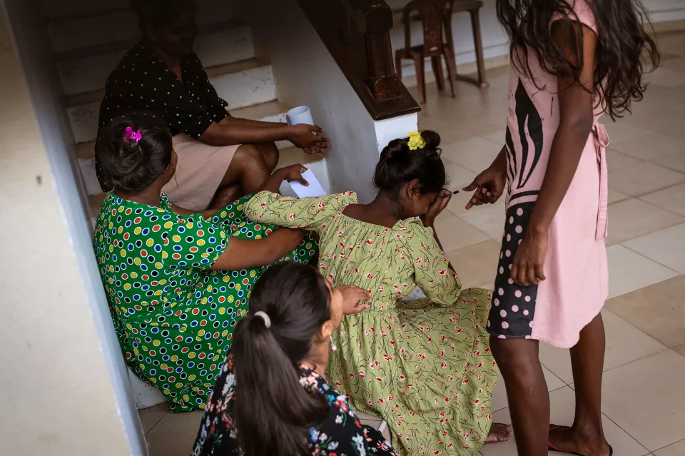  group of girls gathered at the foot of a staircase, leaning in closely together, absorbed in a shared activity.